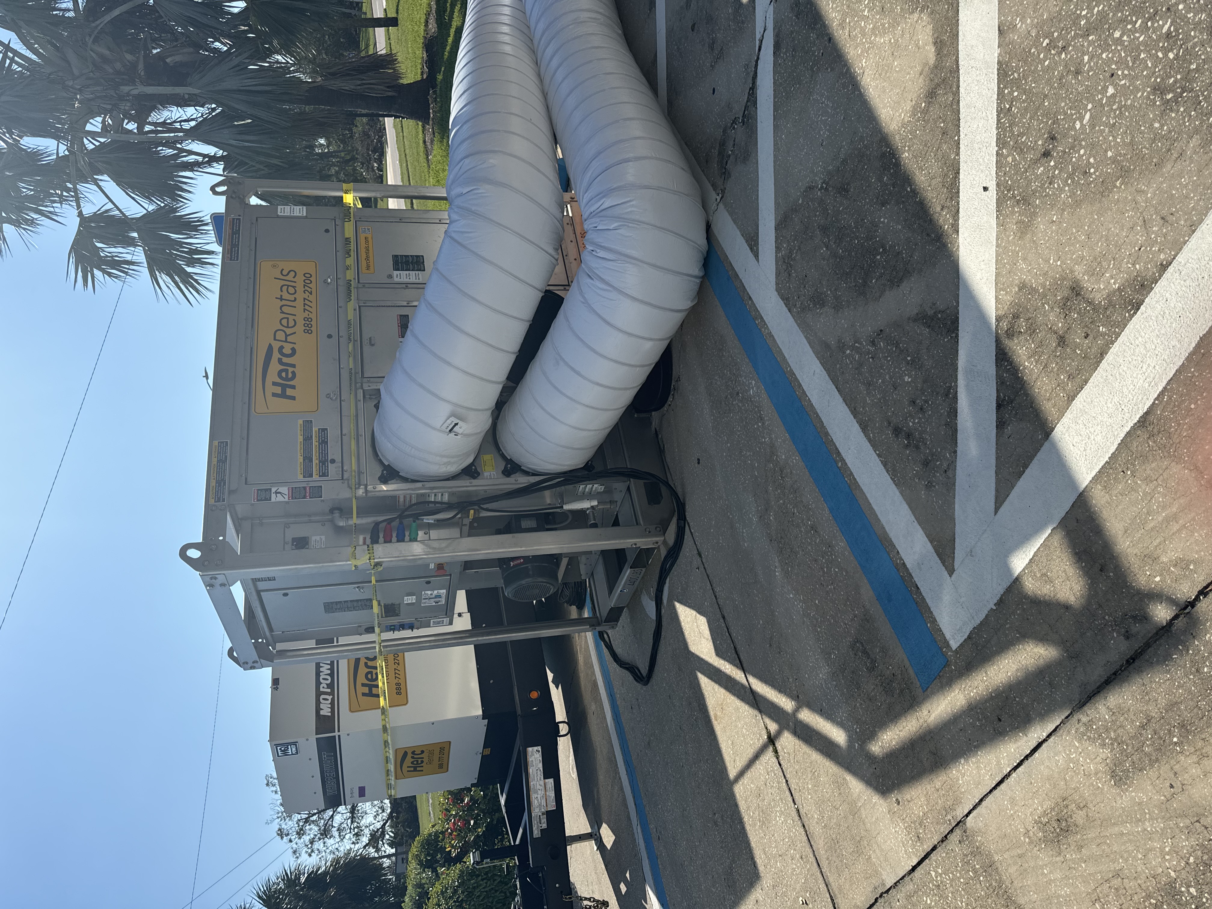 Professional water damage restoration equipment with large white flexible ducting and industrial drying equipment in Minneapolis apartment complex parking lot