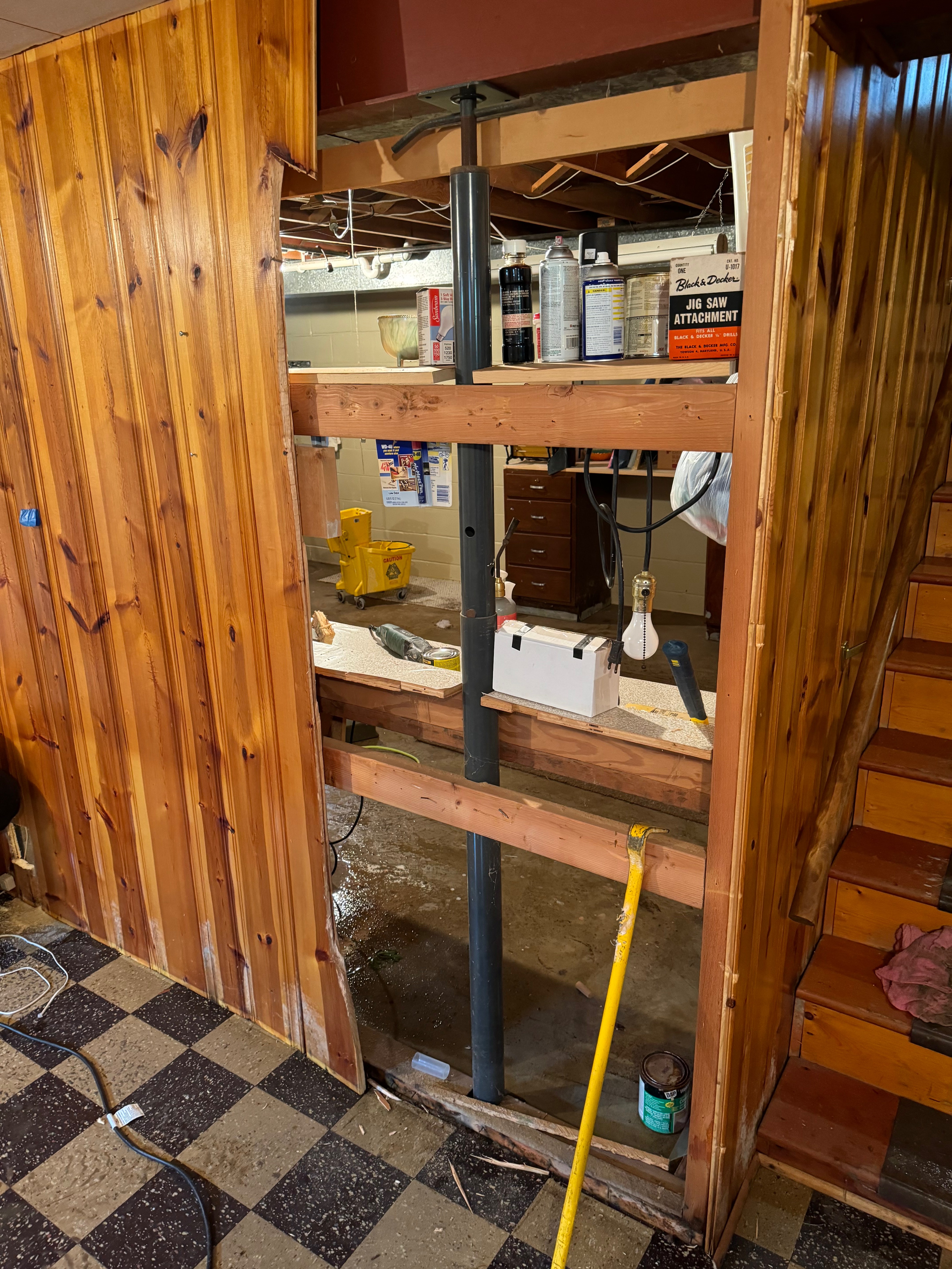 Basement area with wooden support beams and visible water damage with restoration equipment and supplies for structural repair