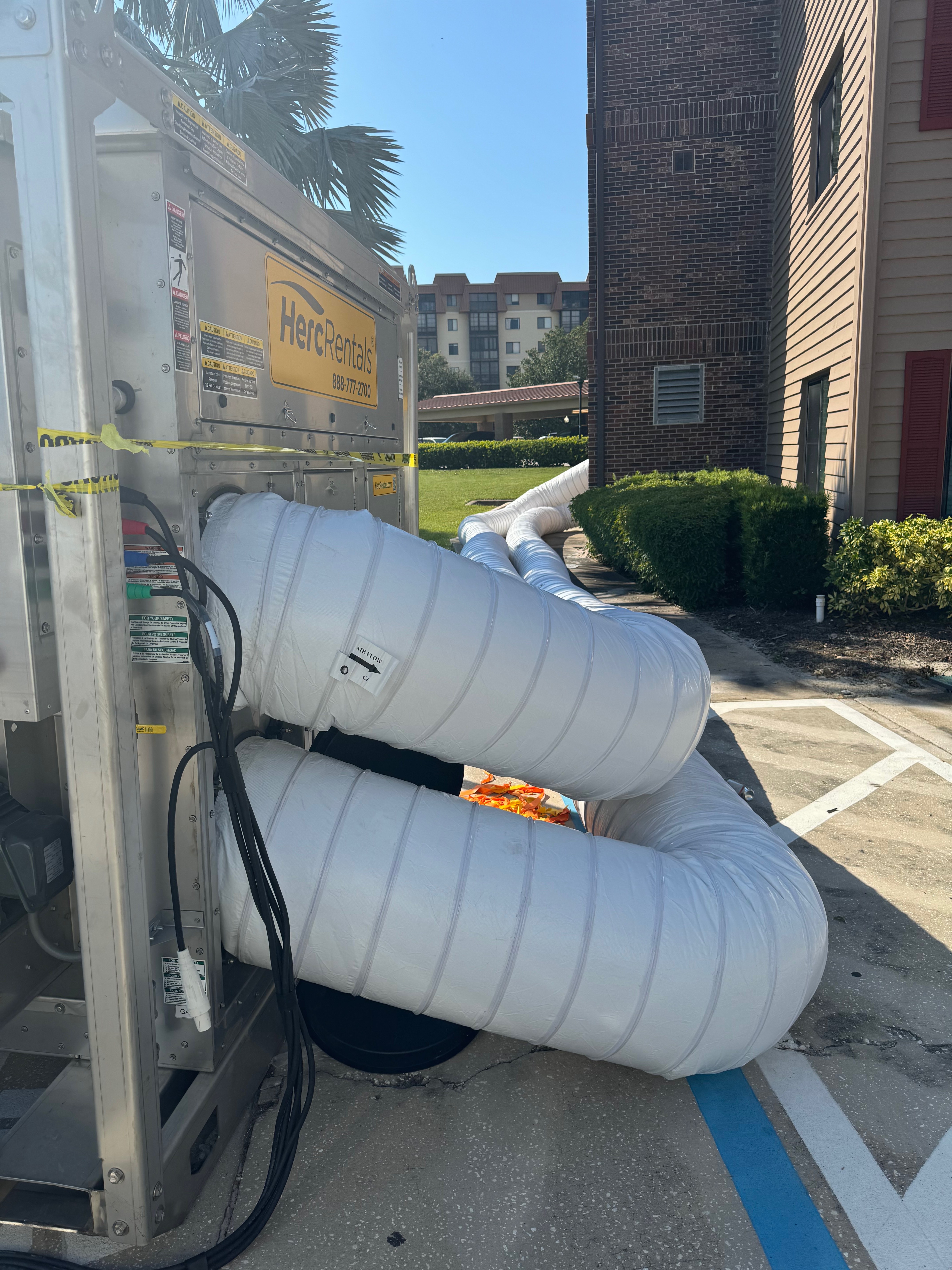HercRentals water damage restoration equipment with white flexible ducting in Bloomington residential parking area